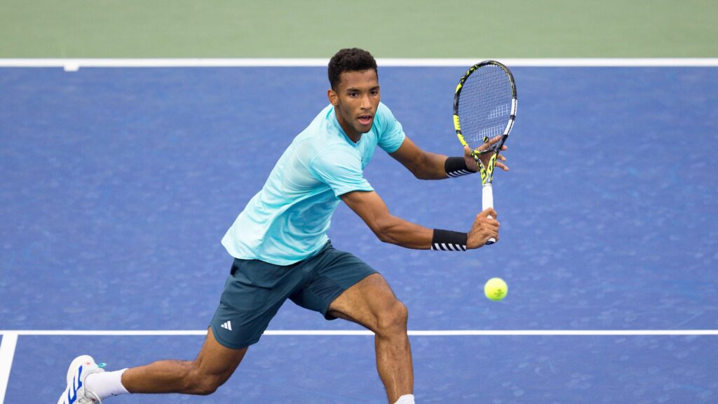 Felix Auger-Aliassime reaches for a backhand volley.