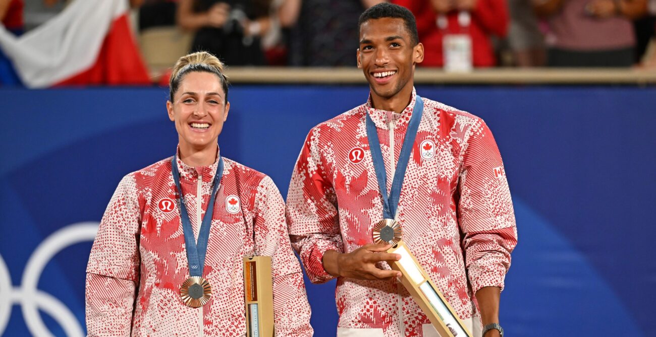 Gabriela Dabrowski and Felix Auger-Aliassime stand on the podium wearing their Olympic bronze medals and smile.