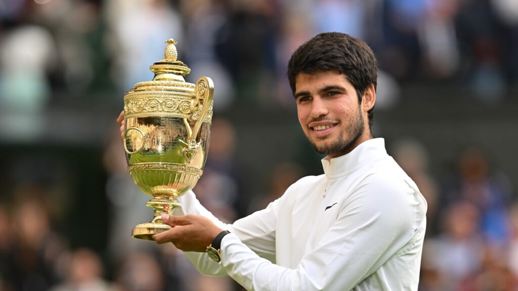 Carlos Alcaraz holds up the Wimbledon trophy.