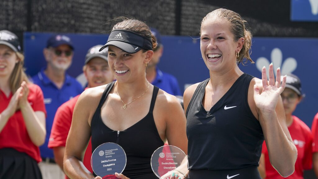 Ariana Arseneault (right) waves while Mia Kupres (left) holds her trophy in Granby.