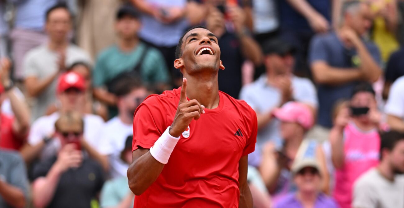 Felix Auger-Aliassime wags a finger at the sky and smiles. He beat Casper Ruud on Thursday at the Olympics.