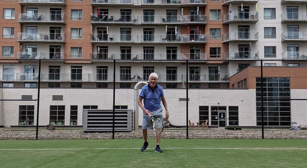 A senior tennis player on court smiling