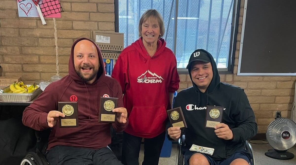 After winning a wheelchair doubles title, Mitch McIntyre (right) holds up his trophy.