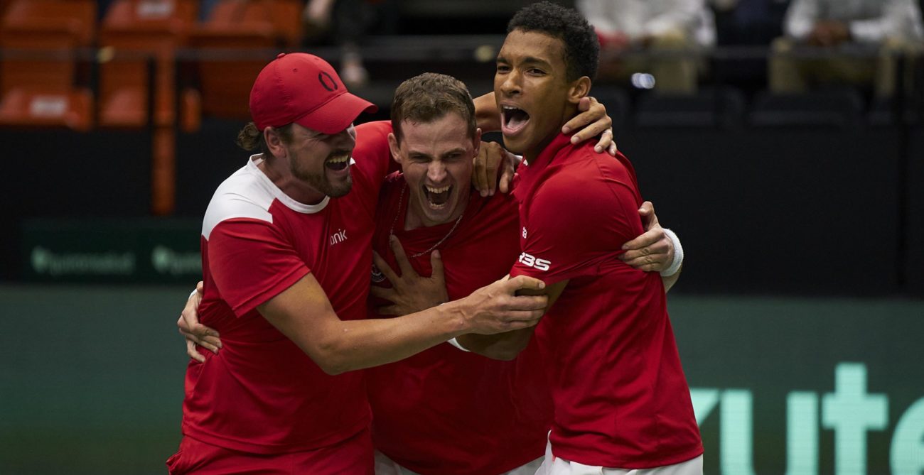 Felix Auger Aliassime, Vasek Pospisil, and Frank Dancevic celebrate victory over Spain in a group hug