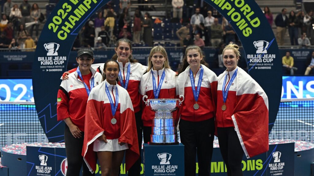 From left to right, Heidi El Tabakh, Leylah Fernandez, Rebecca Marino, Eugenie Bouchard, Marina Stakusic, and Gabriela Dabrowski wear their medals and stand behind the Billie Jean King Cup trophy.