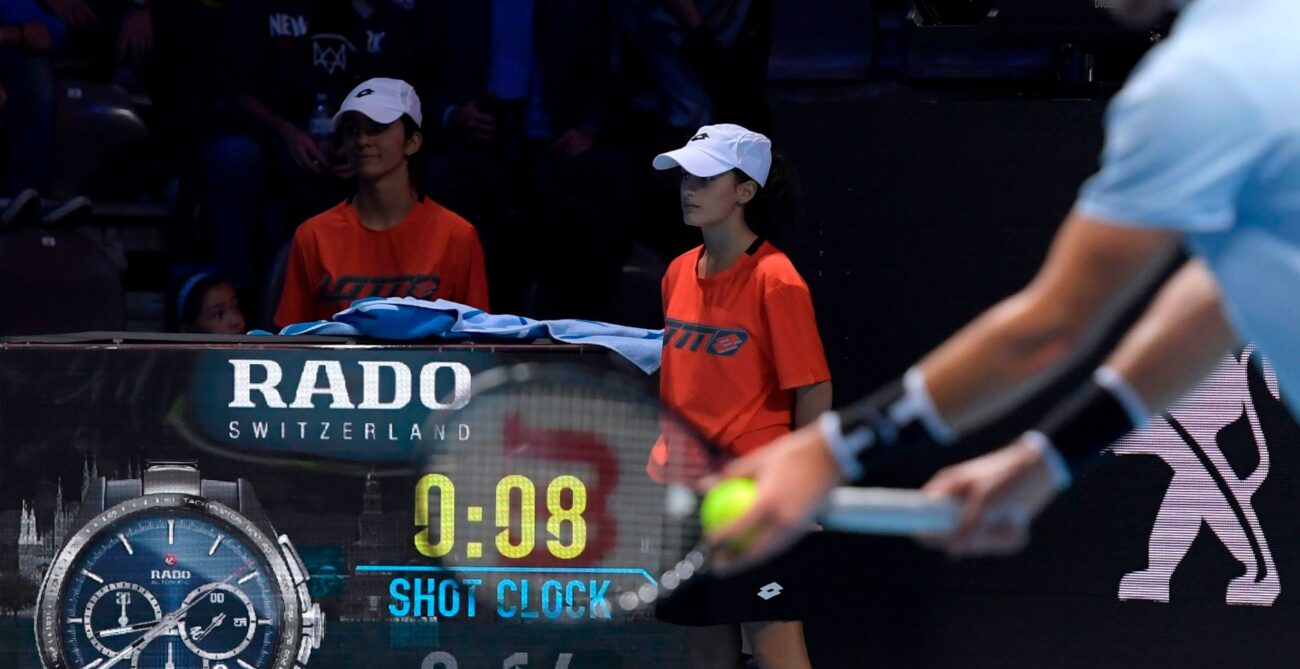 A player prepares to serve with the shot clock visible in the background.