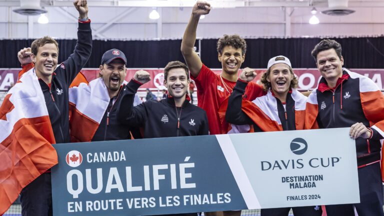 Team Canada holds up a "Qualified" sign after Gabriel Diallo won the clinching match at the Davis Cup.