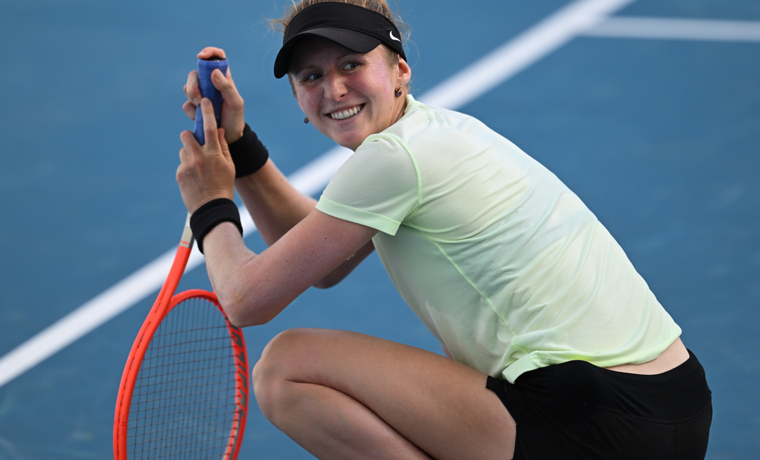 Katherine Sebov kneels on the court and turns and smiles.